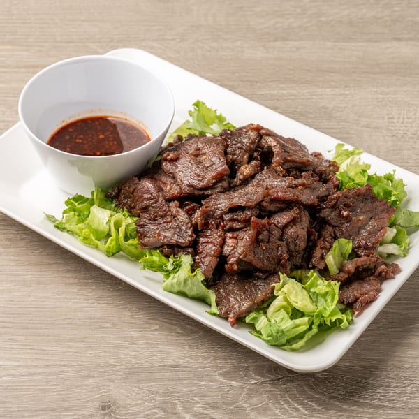 Tasty Thai's grilled beef slices on lettuce with a side of spicy dipping sauce.
