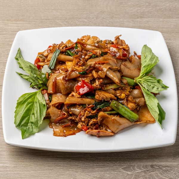 Tasty Thai's Pad See Ew, a dish of wide rice noodles, chicken, and vegetables, garnished with basil.