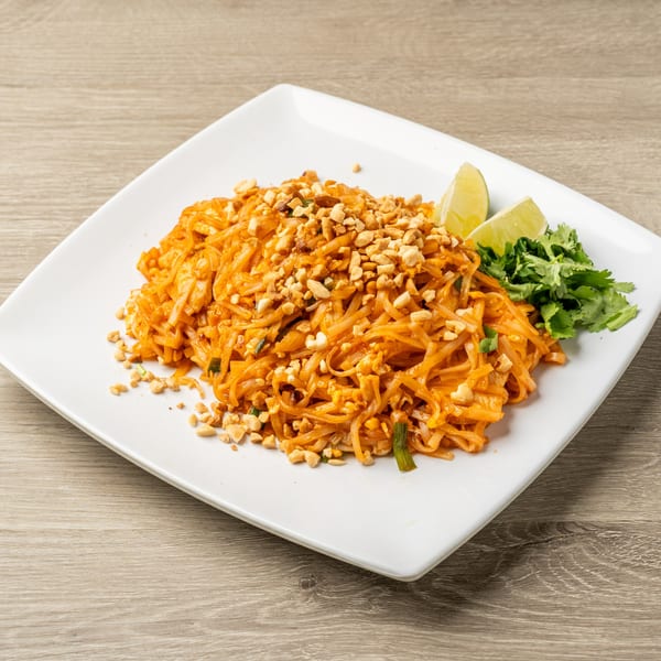 A plate of Tasty Thai's Pad Thai, garnished with crushed peanuts, lime wedges, and cilantro.
